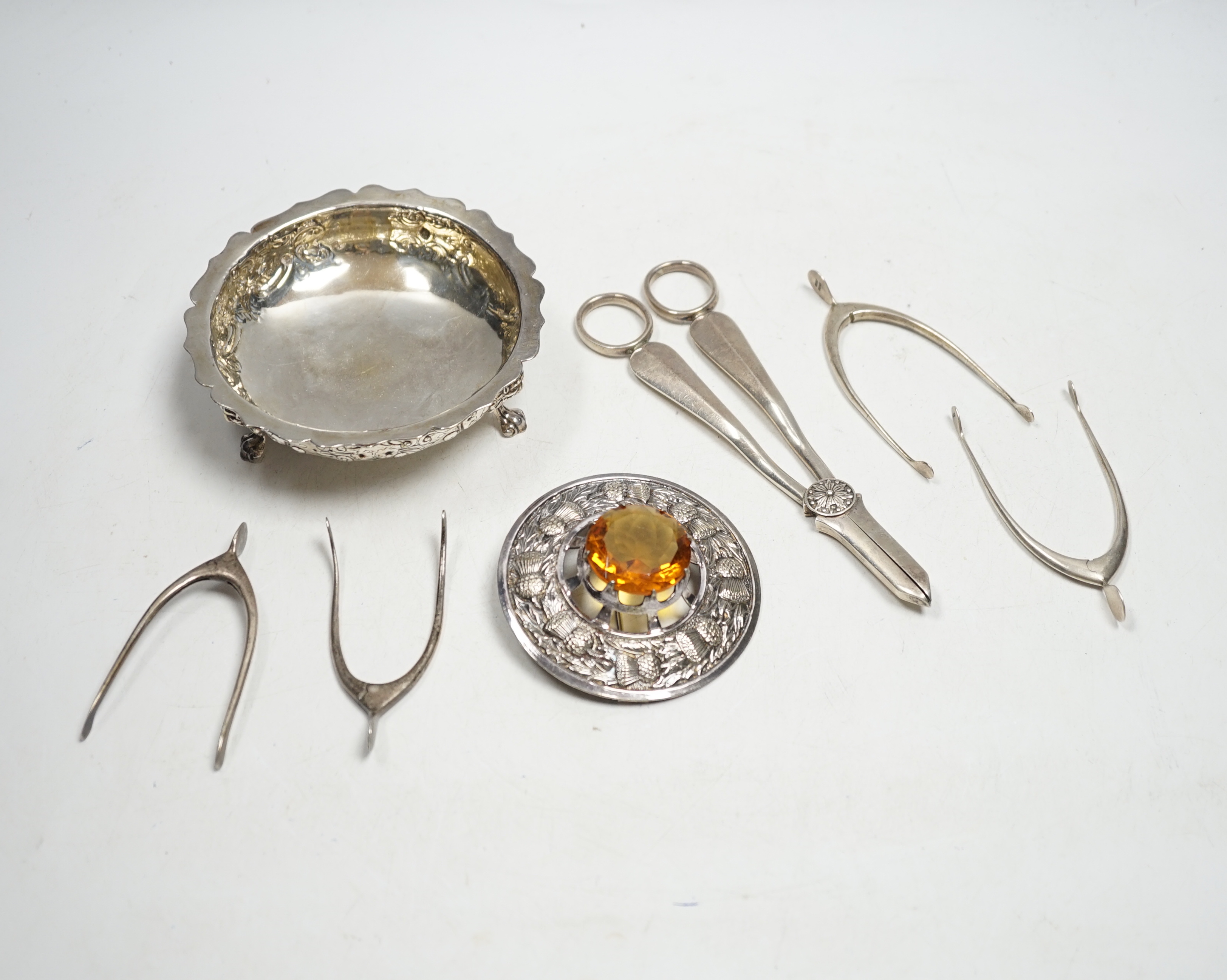 A pair of George V silver grape shears, Mappin & Webb, Sheffield, 1935, 17.2cm, four assorted pairs of early to mid 20th century silver wish bone sugar nips, a plated bowl and a brooch.